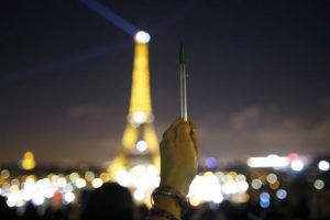 A person holds a pen, symbolising freedom of speech, as lights on the Eiffel Tower start to dim before switching off for five minutes in Paris